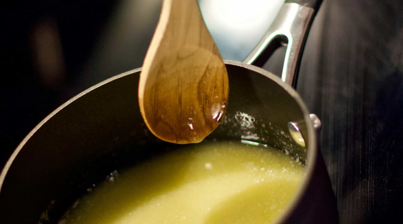 Saucepan with cannabutter and a wooden spoon on top of it.