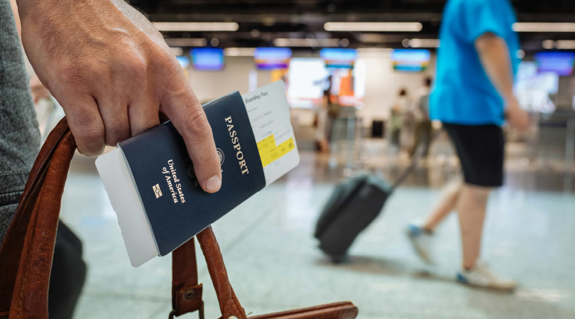 Hand holding a passport in an airport.