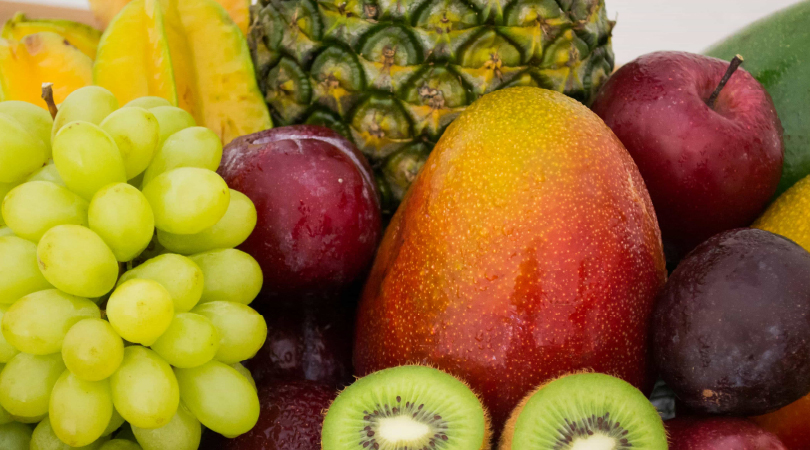 A colorful assortment of flavonoid-rich fruits including grapes, apples, kiwi, mango, pineapple, plum, and starfruit—known for their antioxidant and wellness-supporting properties.